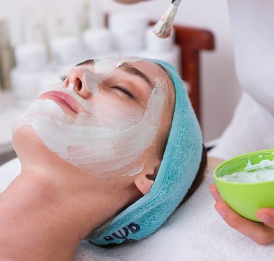 woman lying on blue towel with white cream on face