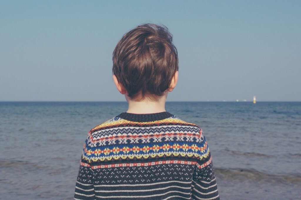 person wearing multicolored striped floral sweater facing the sea scoliosis
